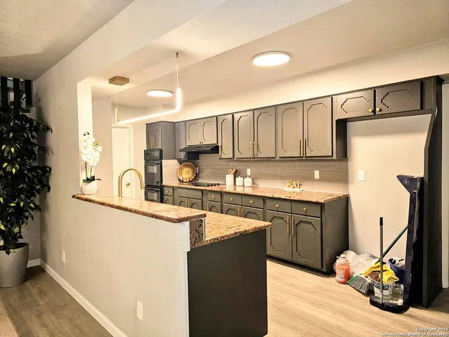 a kitchen with stainless steel appliances granite countertop a refrigerator a sink dishwasher and white cabinets with wooden floor