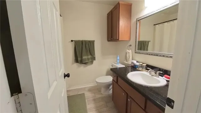 a bathroom with a granite countertop sink toilet and mirror