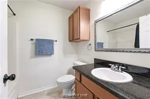 a bathroom with a granite countertop toilet sink and mirror