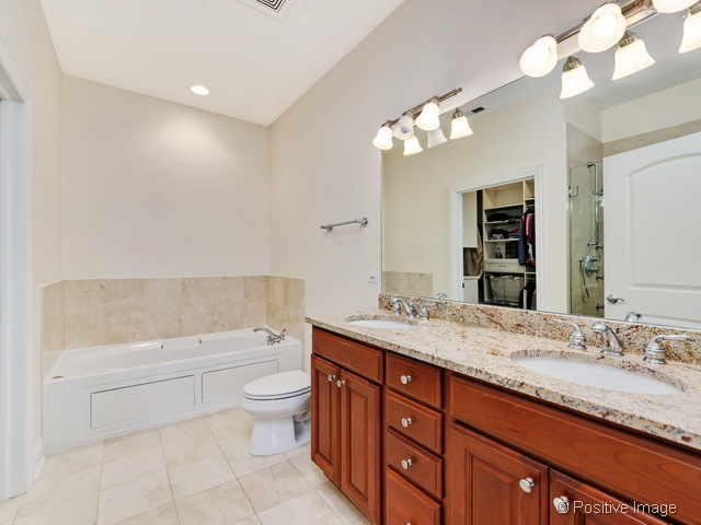 1453 West Irving Park Road, Unit 304 Chicago, IL 60613 - Photo 11 of 17 a bathroom with a granite countertop sink a toilet a large mirror and shower
