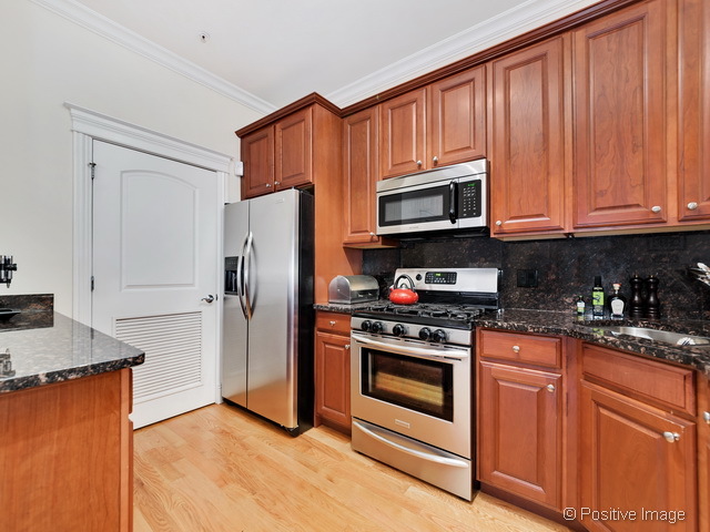 1453 West Irving Park Road, Unit 304 Chicago, IL 60613 - Photo 8 of 17 a kitchen with granite countertop wooden cabinets and stainless steel appliances