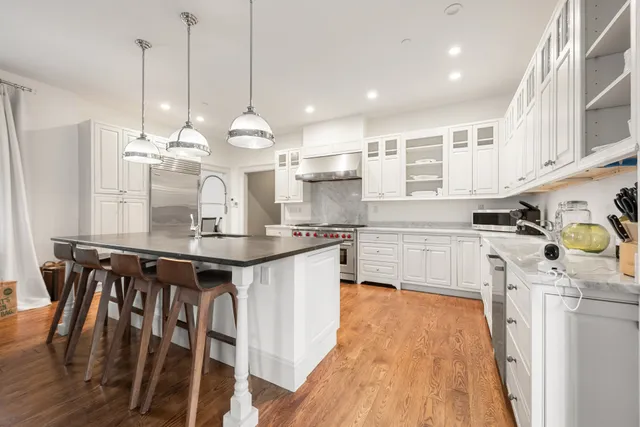 a kitchen with kitchen island granite countertop a sink a counter space appliances and cabinets