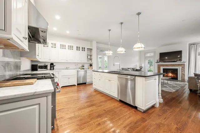 a kitchen with stainless steel appliances granite countertop a stove a sink and a wooden floor
