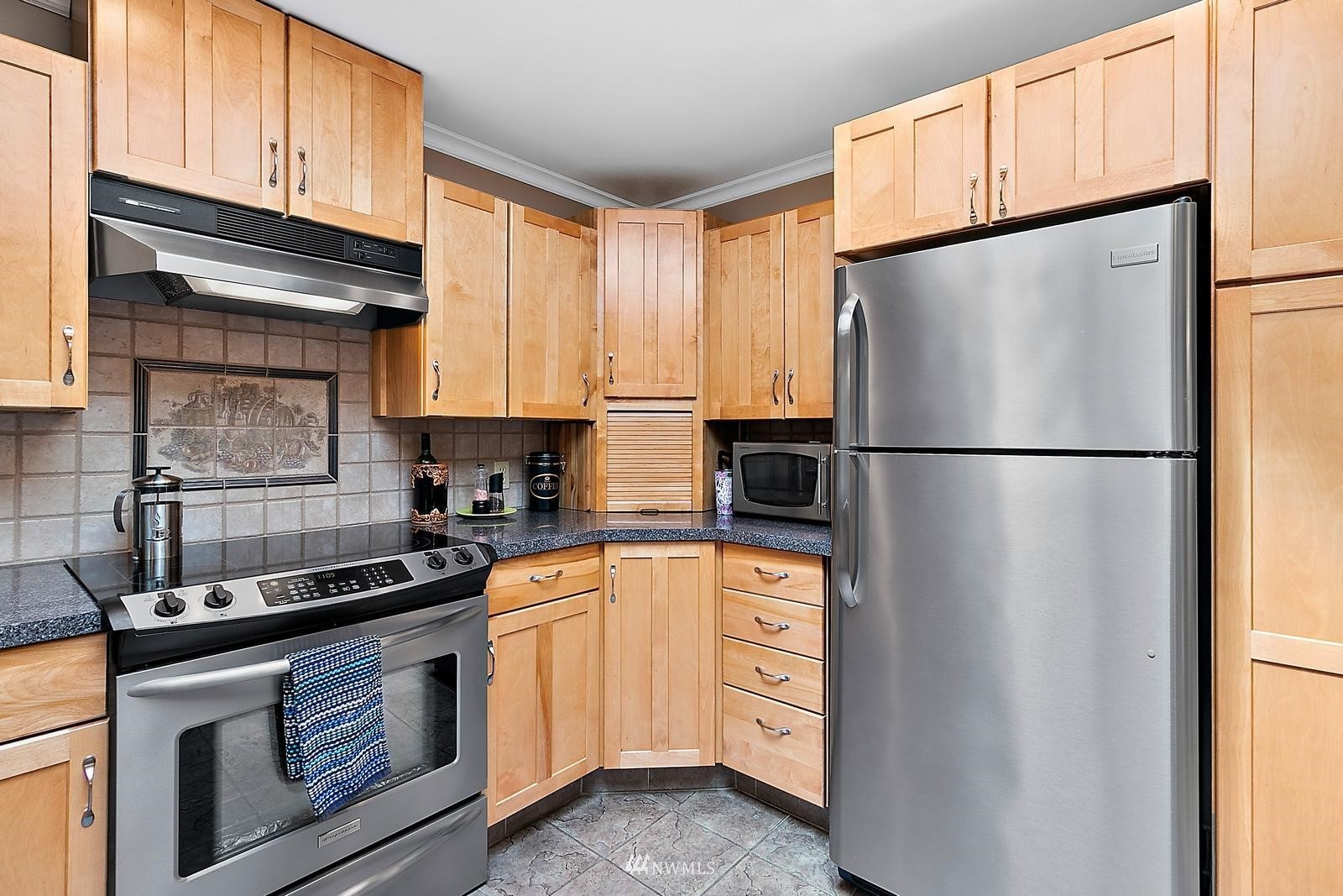 509 Roe Street Steilacoom, WA 98388 - Photo 12 of 40 a kitchen with stainless steel appliances granite countertop a refrigerator sink and cabinets