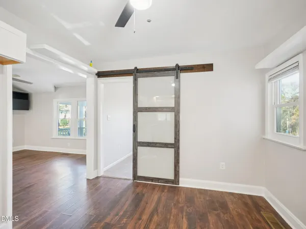 a view of an empty room with wooden floor and a window