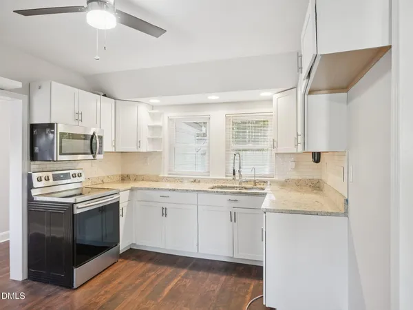 a kitchen with stainless steel appliances granite countertop a sink stove cabinets and refrigerator