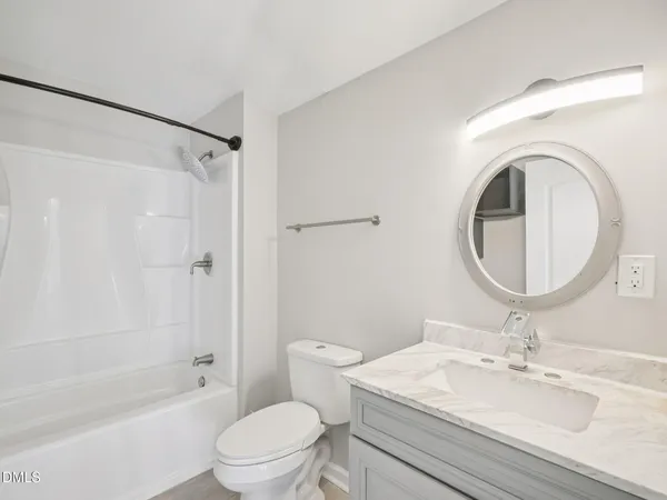 a bathroom with a granite countertop sink toilet a mirror and shower