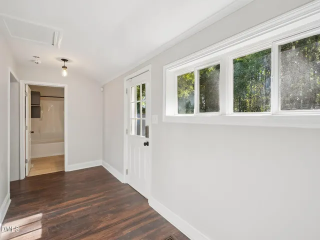 a view of an empty room with wooden floor and a window