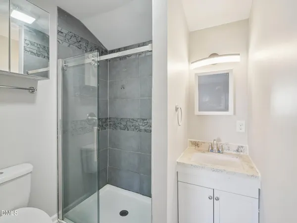 a bathroom with a shower sink vanity mirror and toilet