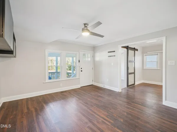 a view of an empty room with wooden floor and a window
