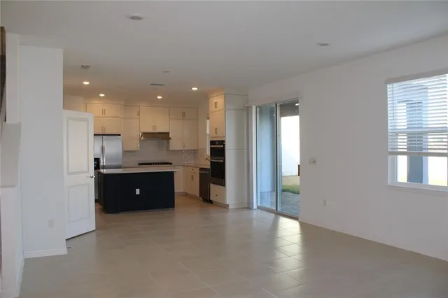 a living room with stainless steel appliances granite countertop furniture a sink a flat screen tv and a window