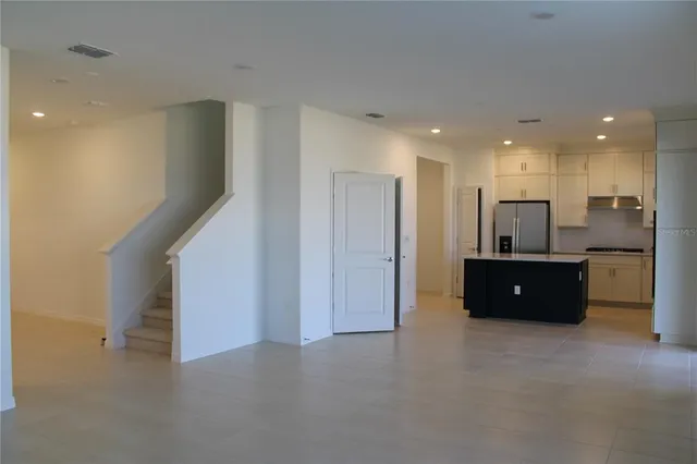 a kitchen with stainless steel appliances granite countertop a refrigerator a sink and white cabinets