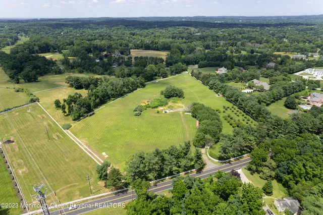 an aerial view of a residential houses with outdoor space and trees