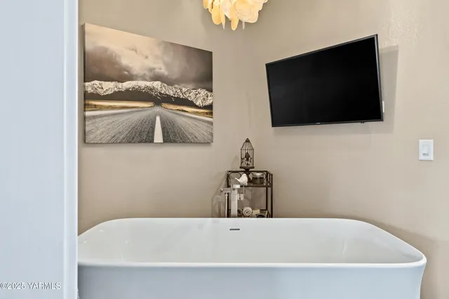a bathroom with a bathtub and a flat screen tv