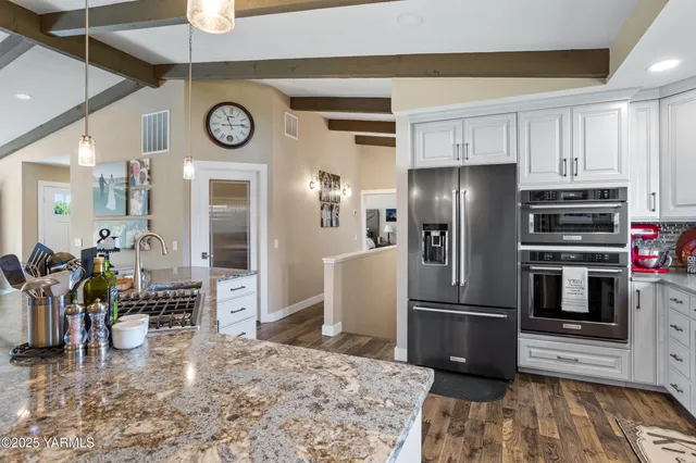 a kitchen with stainless steel appliances granite countertop a refrigerator a stove and a sink with wooden floor