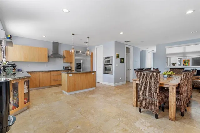 a kitchen with kitchen island stainless steel appliances a refrigerator a stove a sink a dining table and chairs