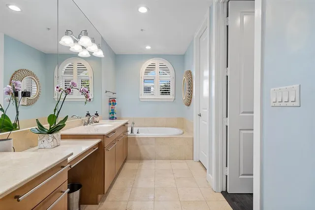 a spacious bathroom with a granite countertop sink a mirror and a bathtub