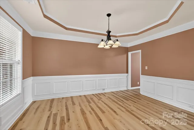 a view of an empty room with wooden floor and a ceiling fan