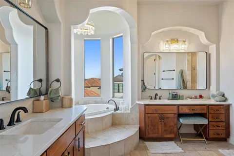 a bathroom with a granite countertop tub a double vanity sink and a large mirror