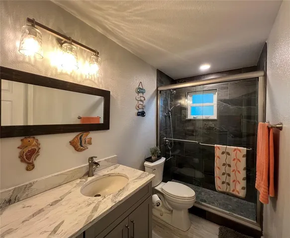 a bathroom with a granite countertop toilet sink and mirror