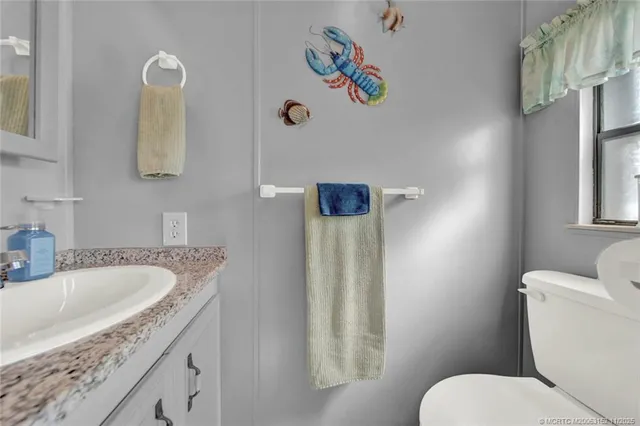 a bathroom with a granite countertop sink a toilet and a mirror