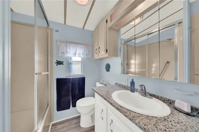 a bathroom with a granite countertop sink toilet a mirror and shower