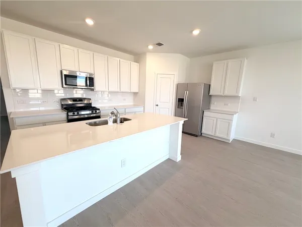 a kitchen with a refrigerator a stove top oven a sink and cabinets