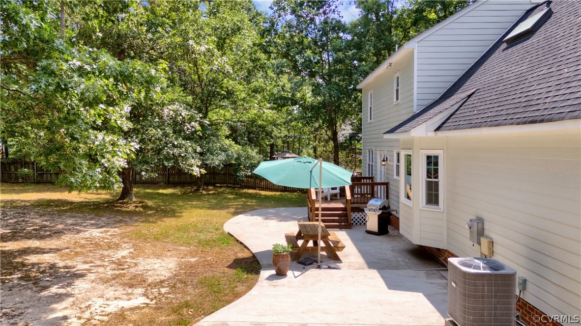 7531 Genuine Risk Lane Midlothian, VA 23112 - Photo 41 of 50 a view of a backyard with table and chairs under an umbrella with wooden fence