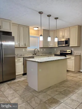 a kitchen with stainless steel appliances granite countertop a sink a stove a refrigerator a microwave a sink and cabinets