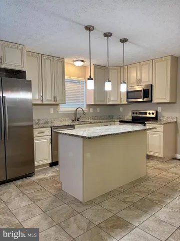 a kitchen with stainless steel appliances granite countertop a sink a stove a refrigerator a microwave a sink and cabinets