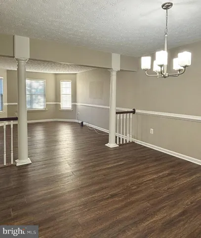 a view of a room with wooden floor chandelier and windows