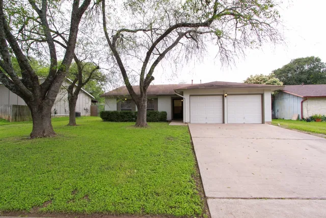 a front view of a house with a garden and tree