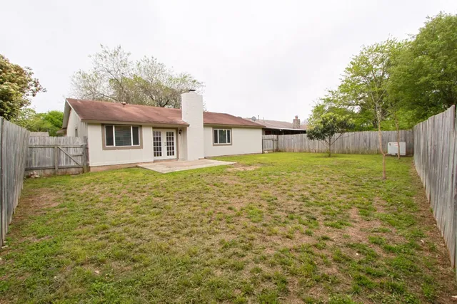 a view of a backyard with large tree and wooden fence