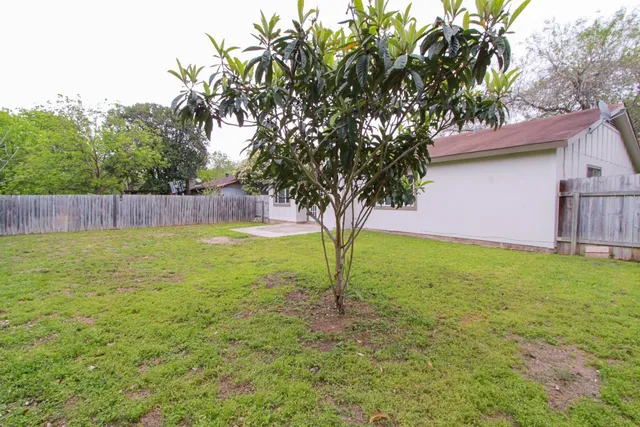 a view of a house with a yard and wooden fence
