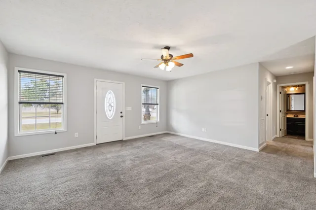 an empty room with fan and windows