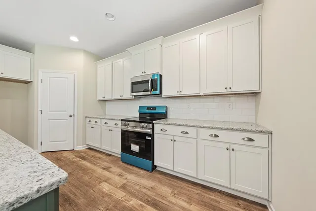 a kitchen with granite countertop white cabinets and stainless steel appliances