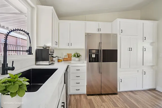 a kitchen with granite countertop a white sink and white cabinets with wooden floor