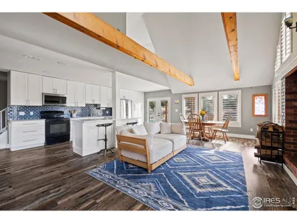 a living room with furniture dining table wooden floor and kitchen view