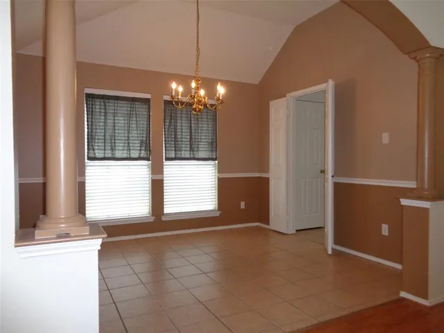 a view of an empty room with a window and chandelier
