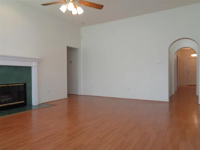 a view of an empty room with wooden floor and a fireplace