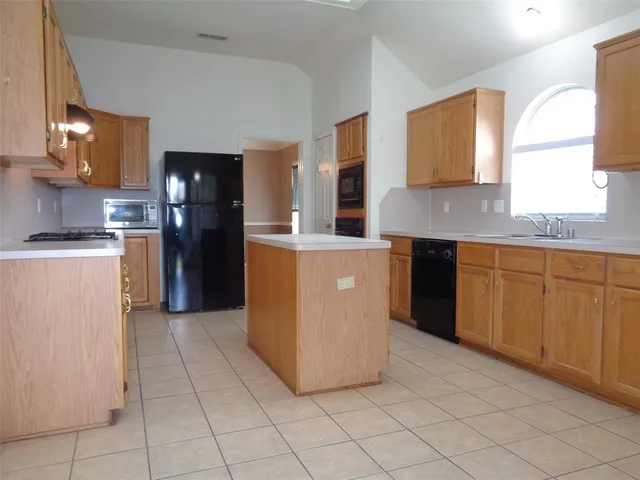 a kitchen with stainless steel appliances granite countertop a stove a refrigerator a sink and dishwasher
