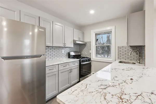 a kitchen with granite countertop a refrigerator sink and cabinets