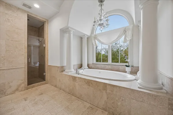 a spacious bathroom with a granite countertop double vanity sink a mirror and a bathtub