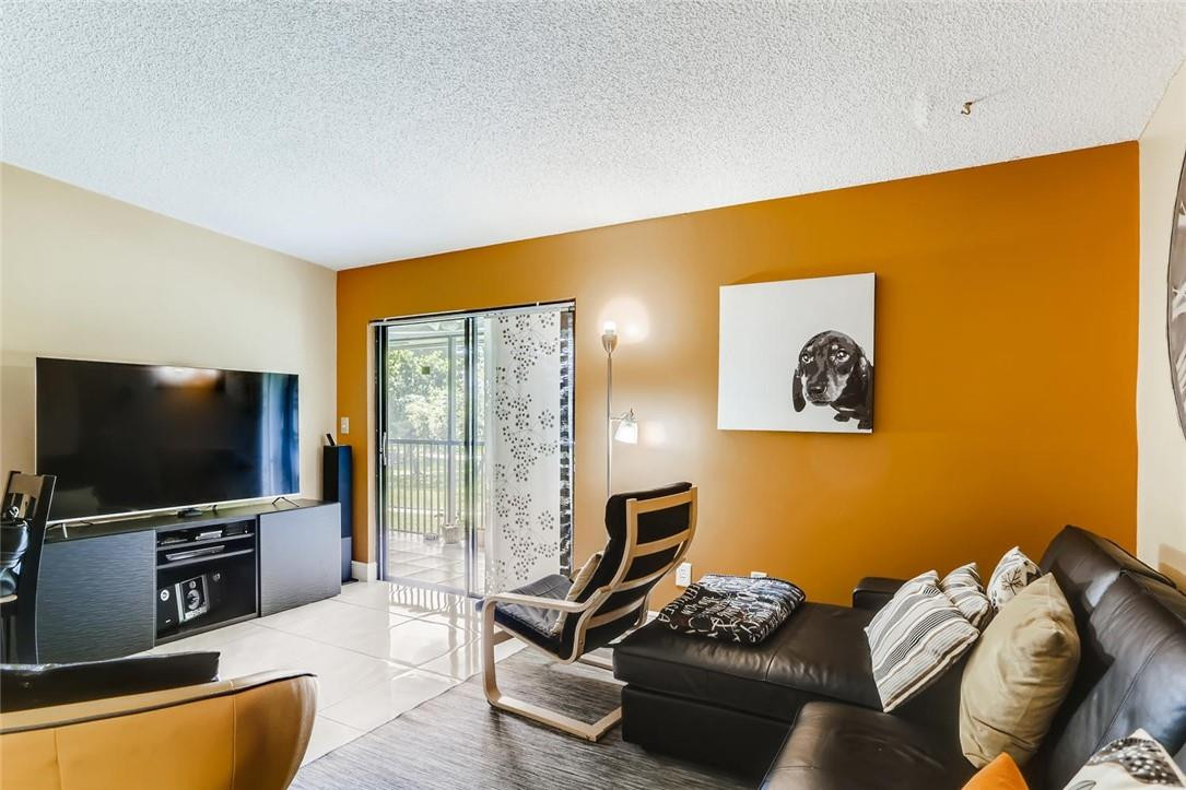 9763 West McNab Road, Unit 214 Tamarac, FL 33321 - Photo 2 of 28 a living room with furniture and a flat screen tv
