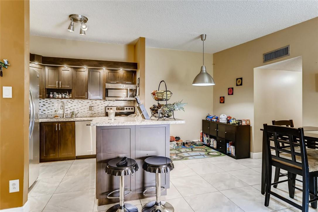 9763 West McNab Road, Unit 214 Tamarac, FL 33321 - Photo 4 of 28 a kitchen with a refrigerator and cabinets