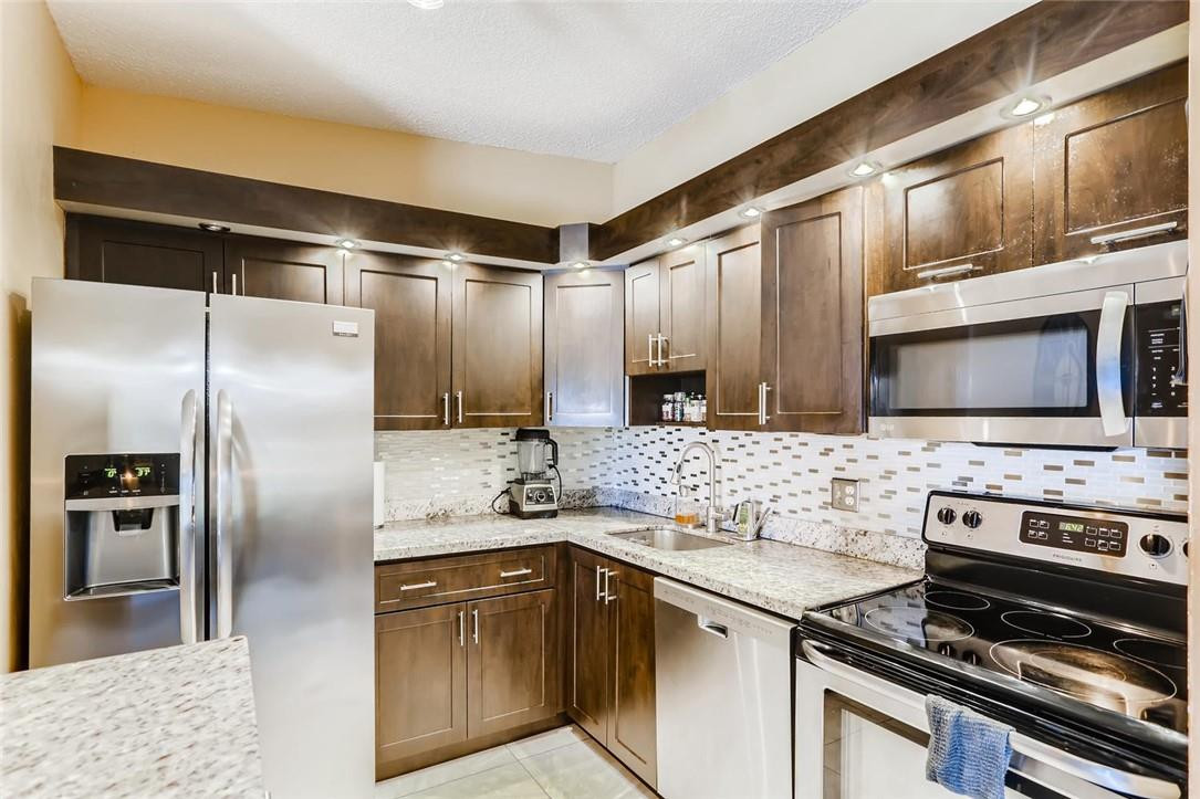 9763 West McNab Road, Unit 214 Tamarac, FL 33321 - Photo 7 of 28 a kitchen with stainless steel appliances granite countertop a refrigerator and a stove top oven