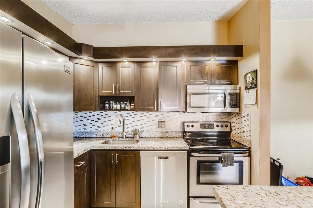 9763 West McNab Road, Unit 214 Tamarac, FL 33321 - Photo 8 of 28 a kitchen with stainless steel appliances granite countertop a refrigerator a stove and a sink with wooden floor