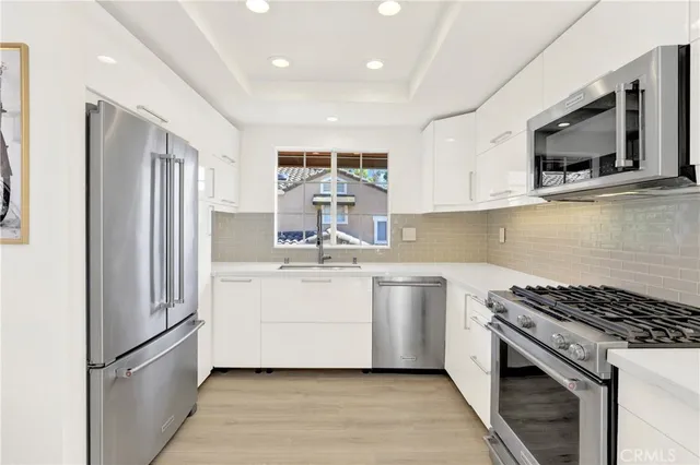 a kitchen with stainless steel appliances white cabinets a sink and a stove