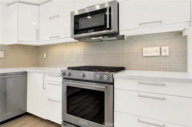 a kitchen with stainless steel appliances granite countertop a stove microwave and cabinets