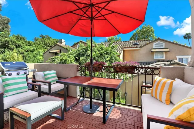 a patio with tables and chairs under an umbrella